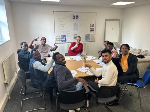 Group of eight people sitting around a table, engaging in discussion and smiling.