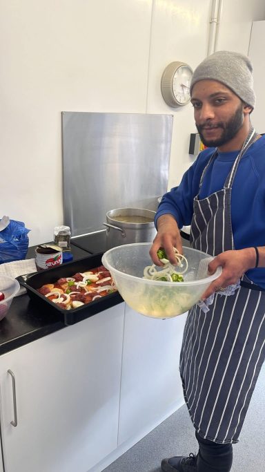 A man in a striped apron preparing vegetables in a kitchen.