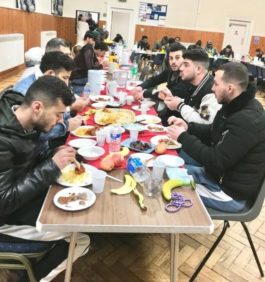 Group of people enjoying a meal around a long table filled with food.