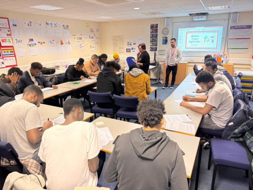 A classroom with students engaged in a lesson, two instructors presenting at the front.